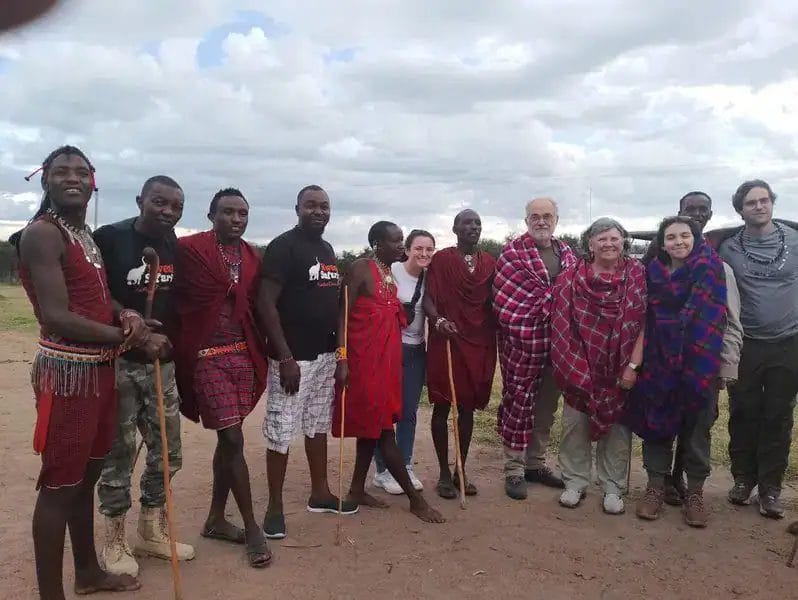 A group of visitors in the maasai village interacting with the locals.