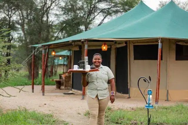 A waitress doing room service in moyo tented camp.